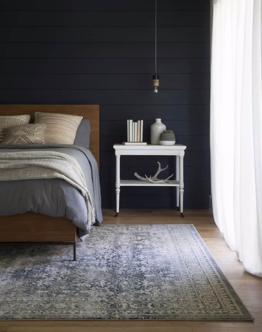 Everly rug from magnolia home in navy bedroom with white side table