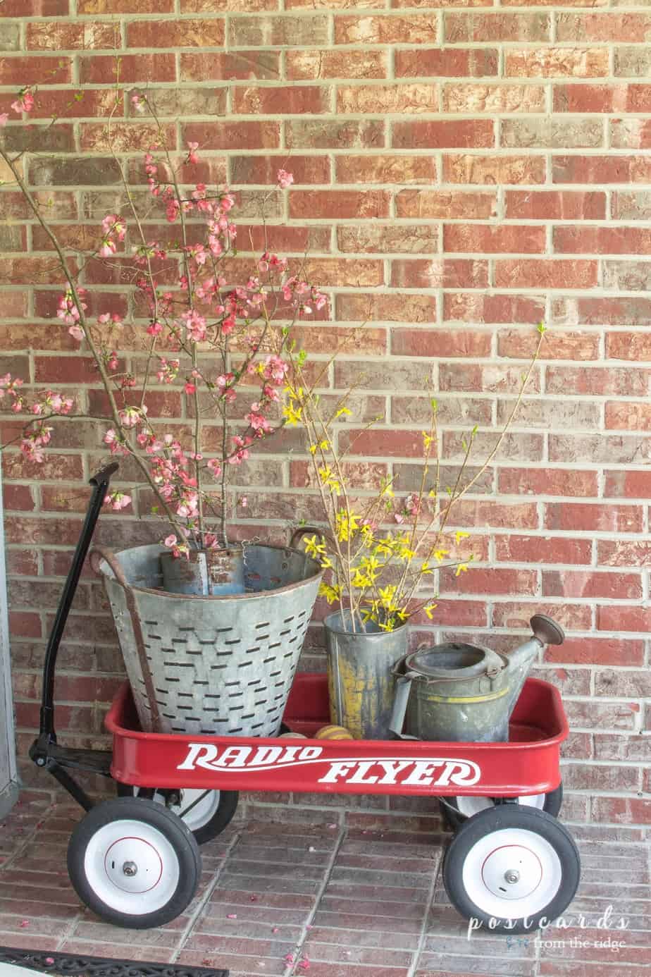red wagon with flowering branches and vintage sap buckets