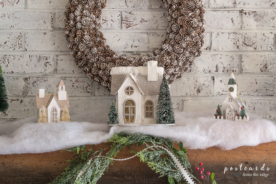 Christmas mantel with pine cone wreath, snowy little houses, cedar garland