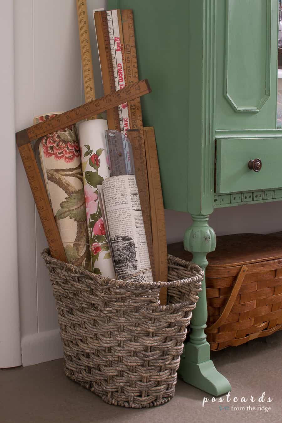 Vintage yardsticks and wallpaper pages in a woven basket