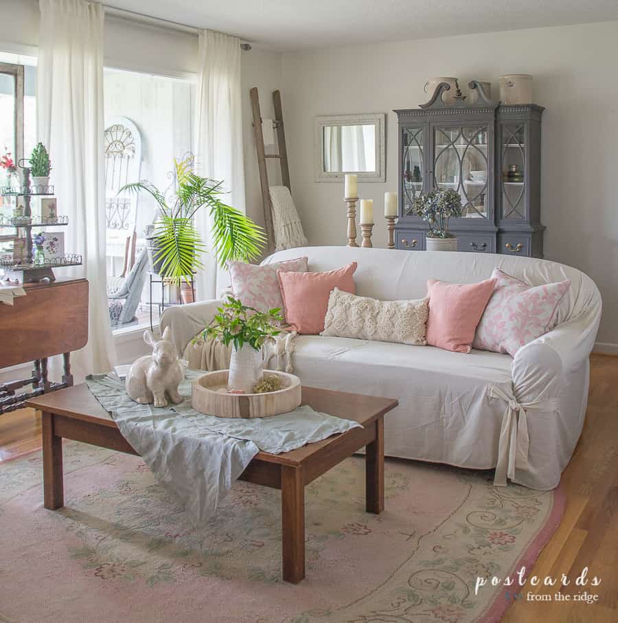 living room with pink rug and pink pillows on a slipcovered sofa