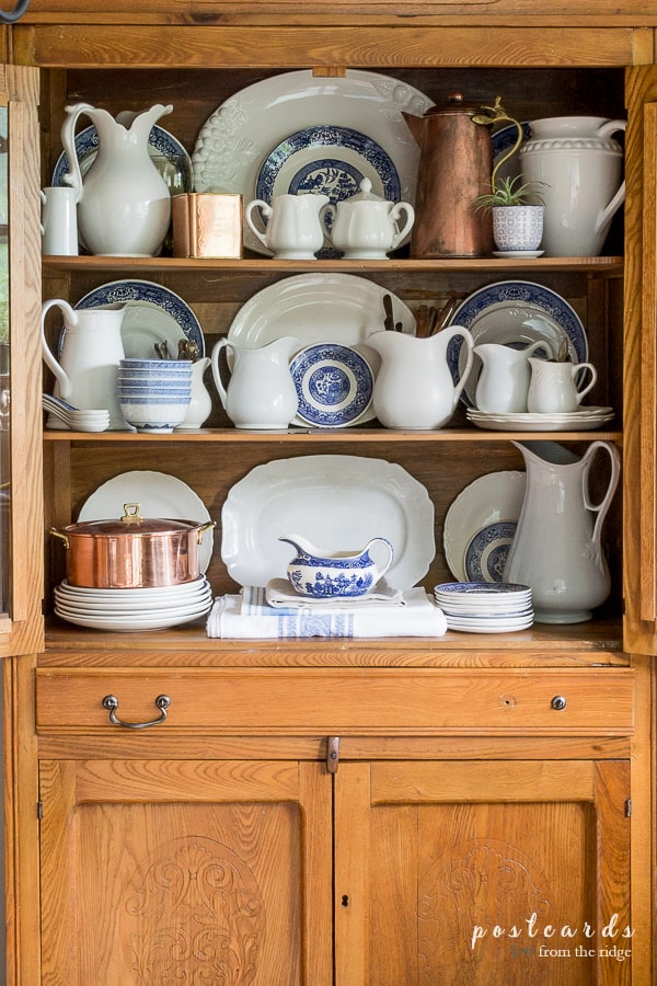 blue willow dishes and white ironstone in an antique oak hutch