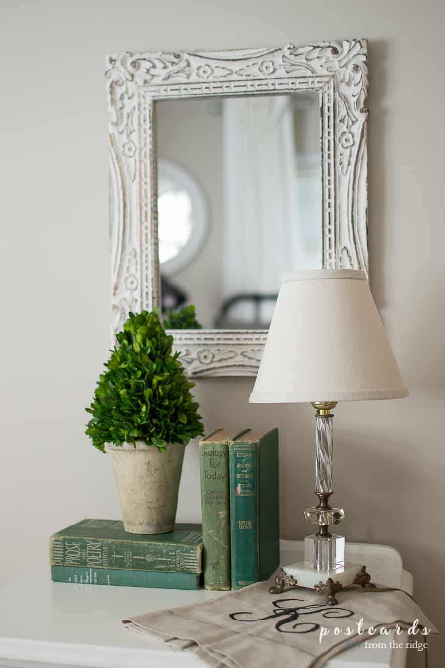 old green books with glass lamp and boxwood topiary