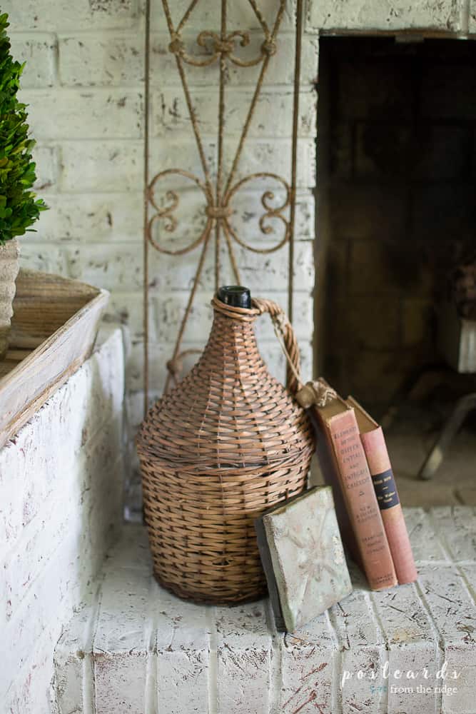 old books and wicker demijohn on fireplace hearth