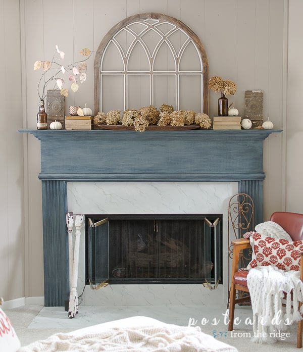 Love this cozy fall fireplace with the painted mantel and arched window. #manteldecor #fallmantel #fireplacedecor