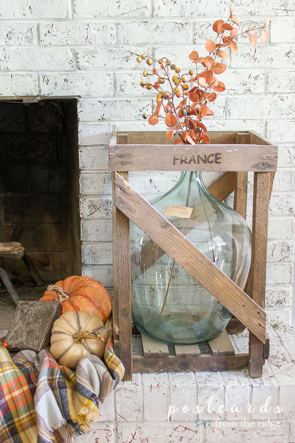 vintage blue demijohn in wood crate with fall decor