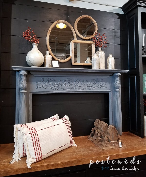 antique mantel with glass jars and wood framed mirrors