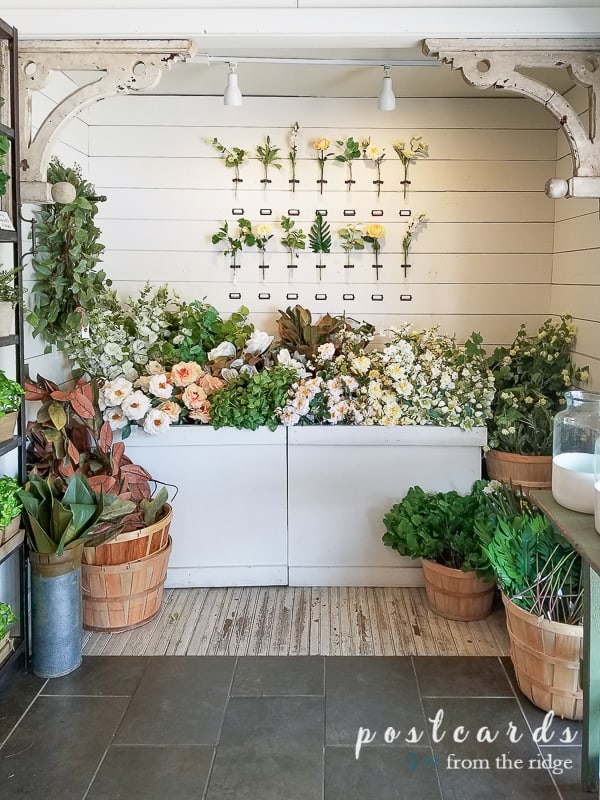 store display with lots of artificial flowers against white wall