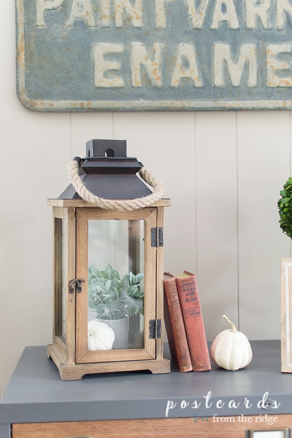 wood and glass lantern with rope handle with vintage books and white pumpkin