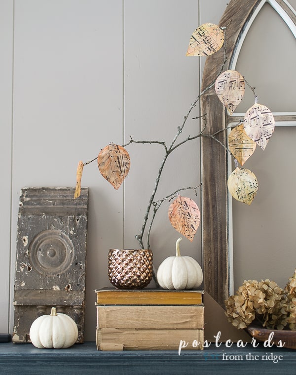 mantel with diy watercolor music sheet leaves and vintage books with baby boo pumpkins