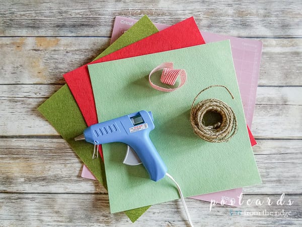 hot glue gun with felt sheets, red stripe ribbon, and roll of wire