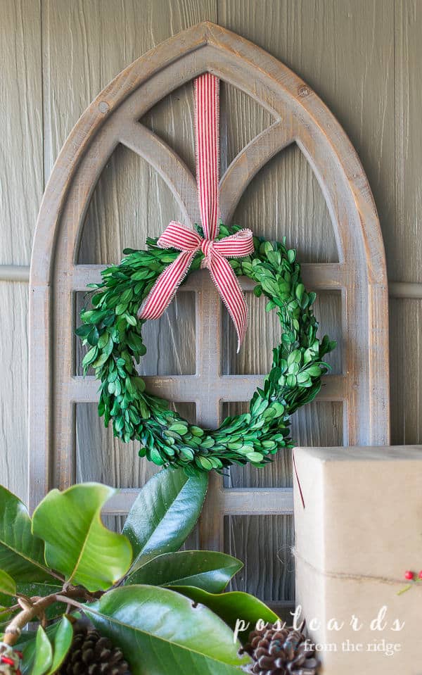preserved boxwood wreath with red striped ribbon on arched wooden cathedral window frame
