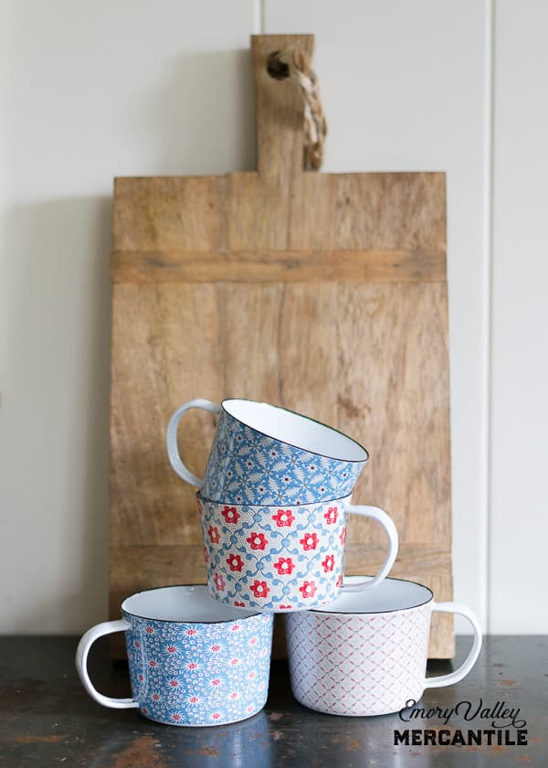 floral enamel mugs in front of a wooden cutting board