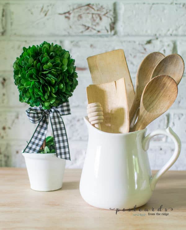 preserved boxwood topiary and vintage wooden spoons in white stoneware pitcher