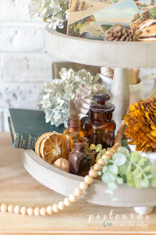 vintage and natural items used as fall decor on a wooden tiered tray
