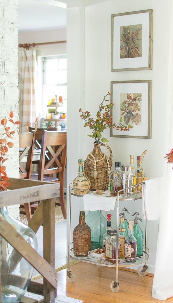 bar cart decorated for fall with vintage art work above