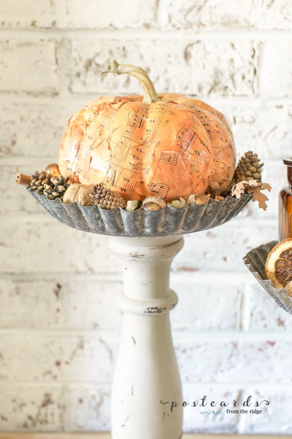 paper mache pumpkin on diy pedestal stand made from wooden candleholder and tart pan