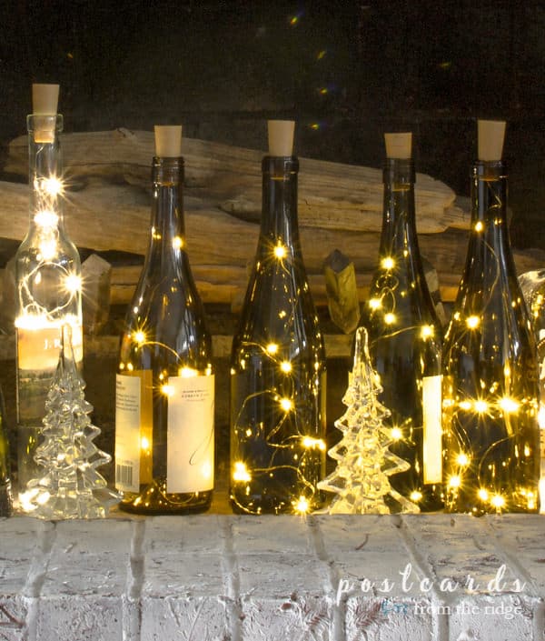 empty wine bottles with fairy lights on a painted brick hearth
