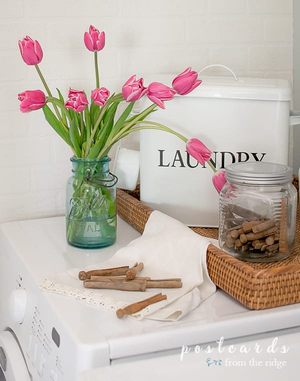 pink tulips in a vintage blue mason jar on a dryer, vintage wooden clothespins in glass jar