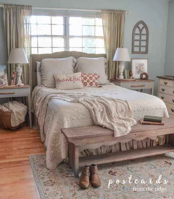 bedroom with French quilt, blue rug, fall pillows