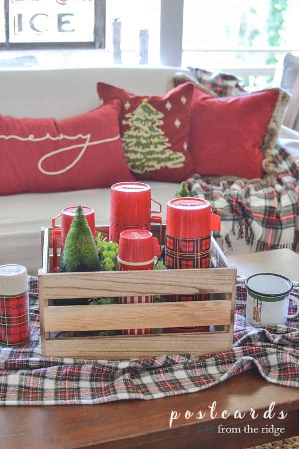 plaid blanket with wooden crate full of vintage red plaid thermoses and bottle brush trees