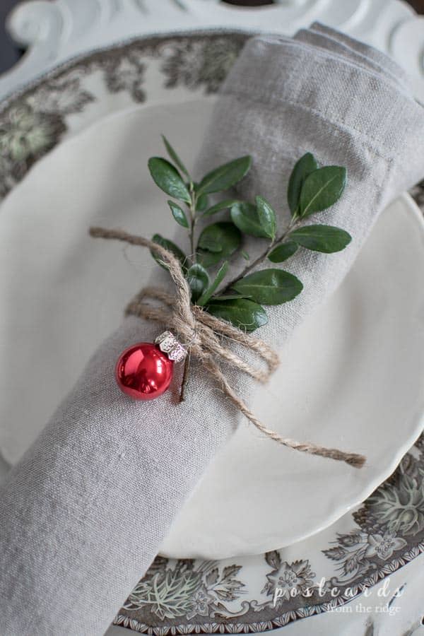 napkin ring made with twine, holly, and a tiny red Christmas ornament