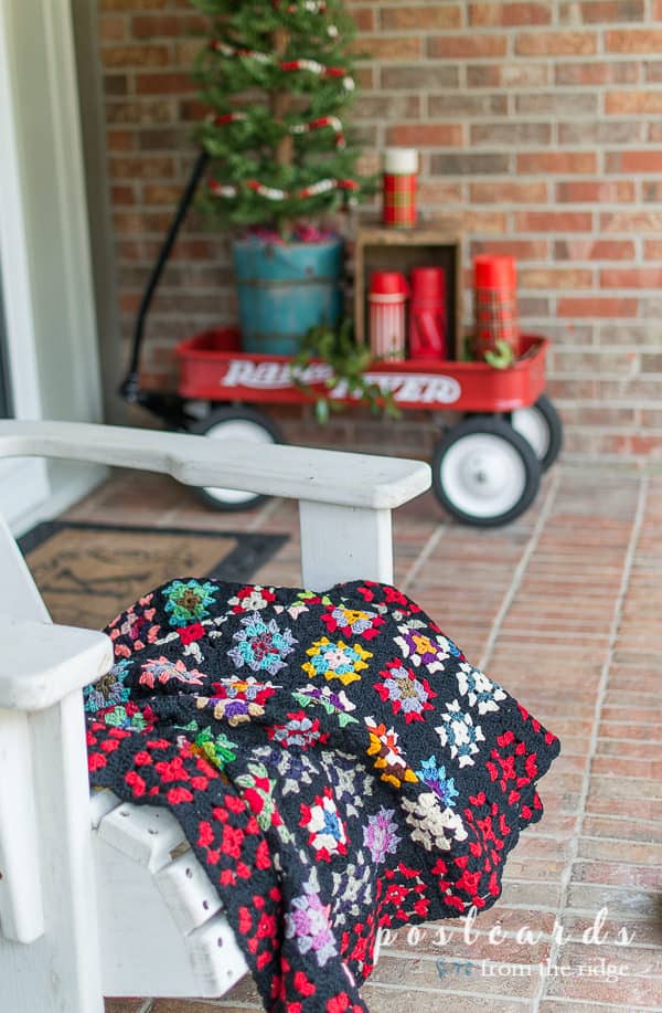 vintage colorful granny square afghan blanket on white porch chair
