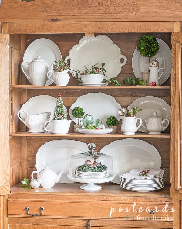vintage white ironstone platters and pitcher in oak hutch with Christmas decor