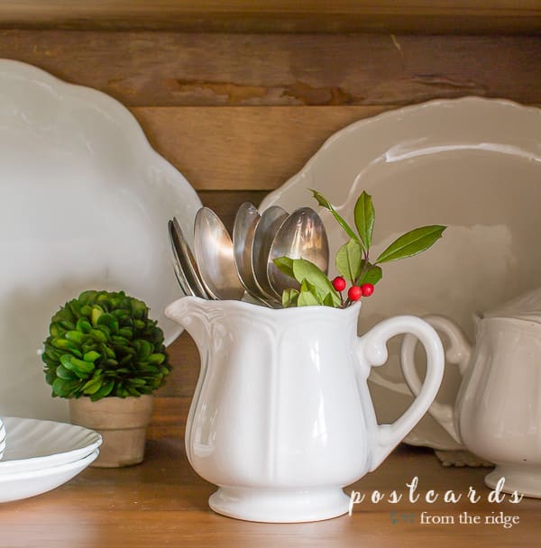 small white ironstone creamer with vintage silver and holly clippings