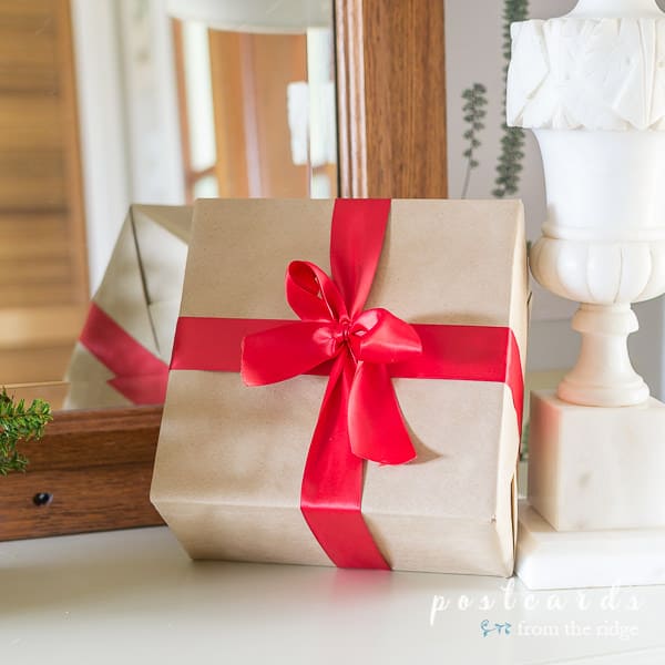small package wrapped with kraft paper and tied with a red satin bow