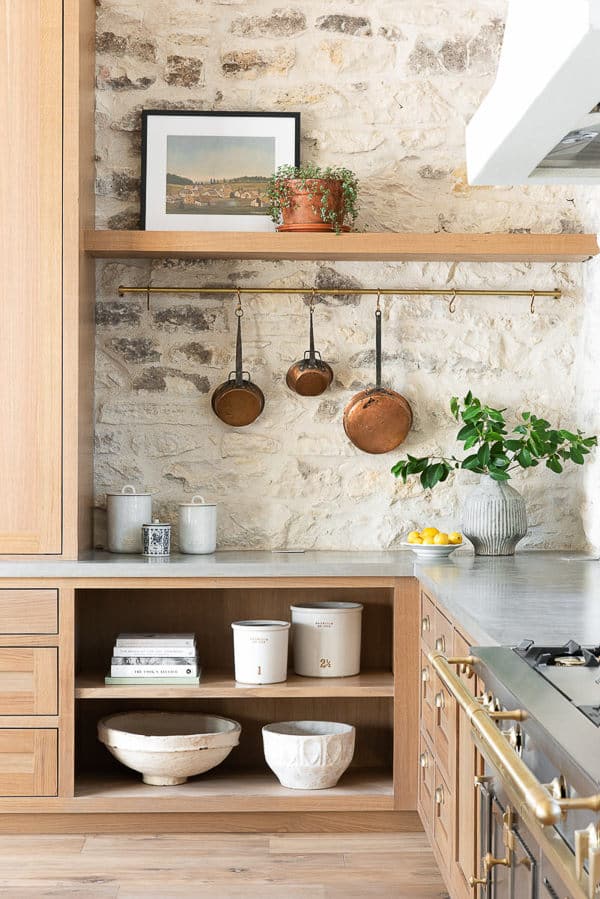 kitchen with light wood cabinets and stone wall with copper pots