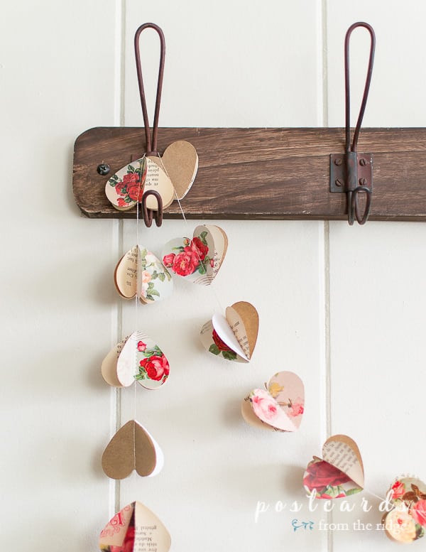 vintage paper heart garland hanging from wood rack with wire hooks
