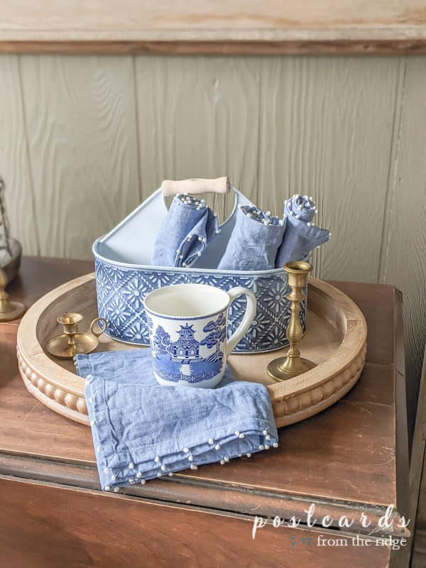 blue willow coffee mug and blue napkins on beaded wooden tray