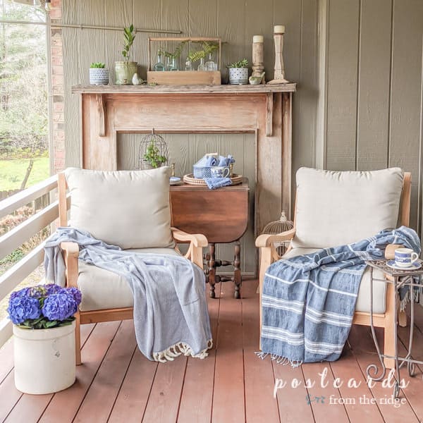 teak outdoor chairs with throw blankets and blue and white decor