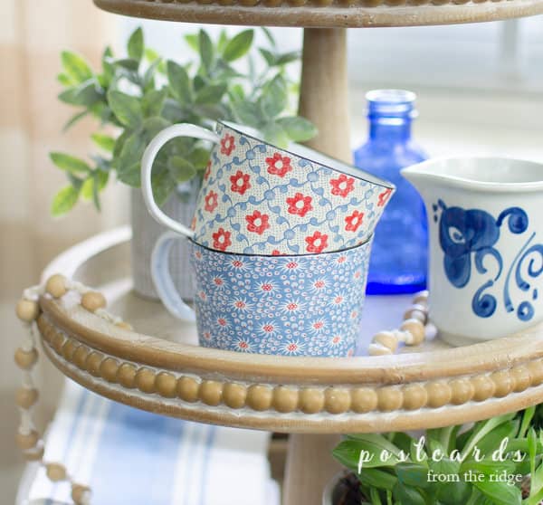 red and blue floral cottagecore enamel mugs in wood three tier tray