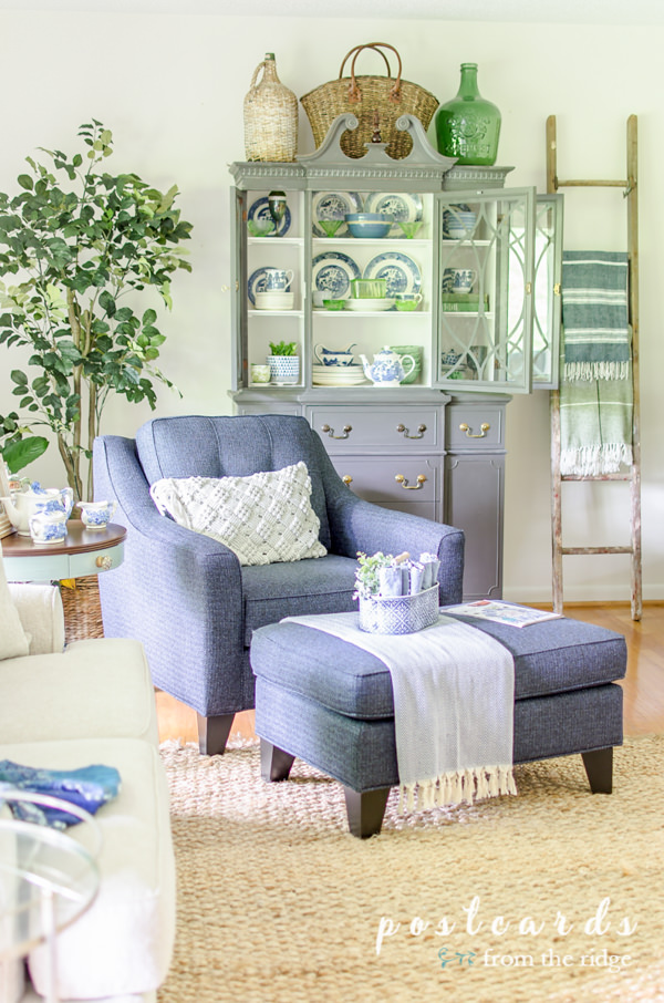 living room with blue and white furniture and old ladder repurposed as a blanket rack