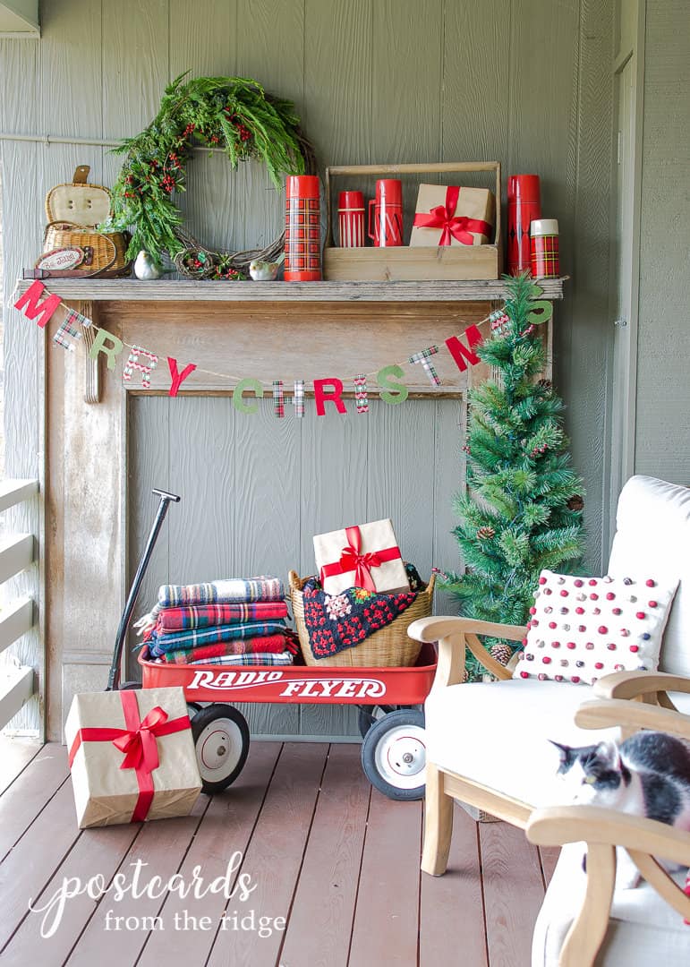 red wagon with plaid blankets and mantel with red thermoses and wreath