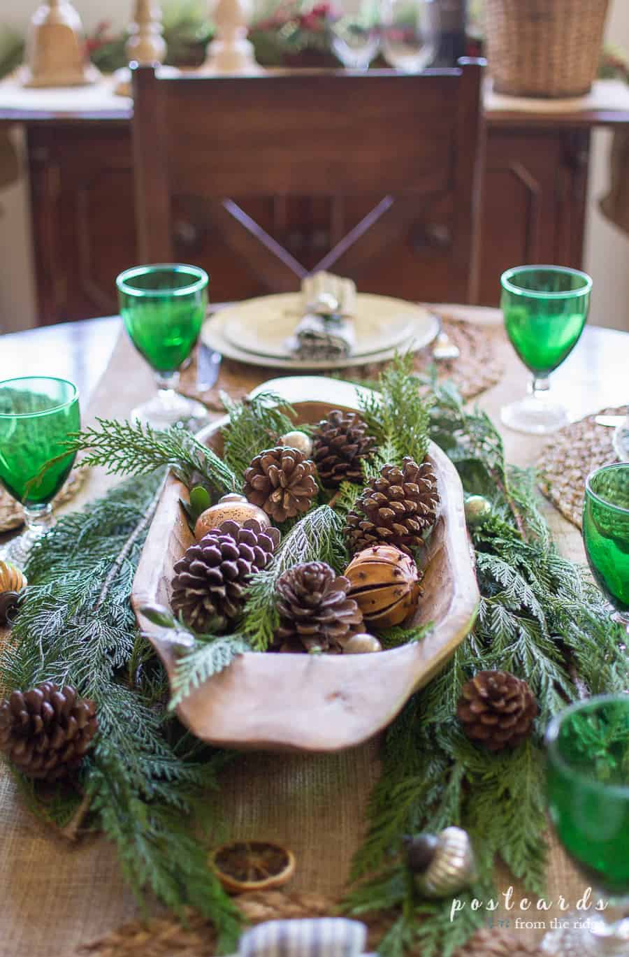 wooden dough bowl filled with pine cones and other natural items on a Christmas table