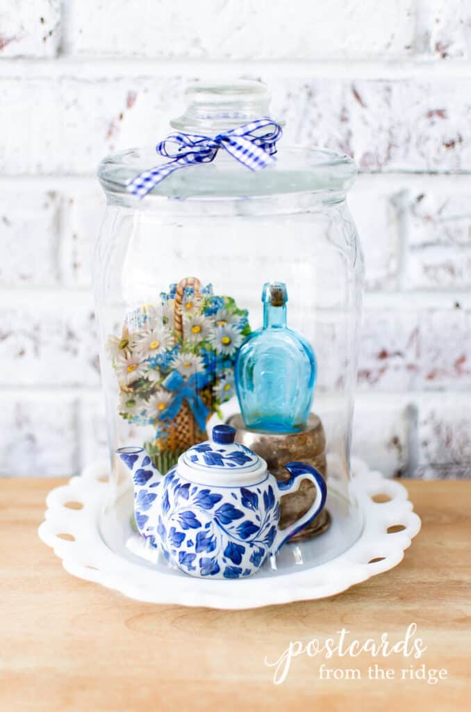 diy glass cloche with tiny teapot and bottle and milk glass plate as base