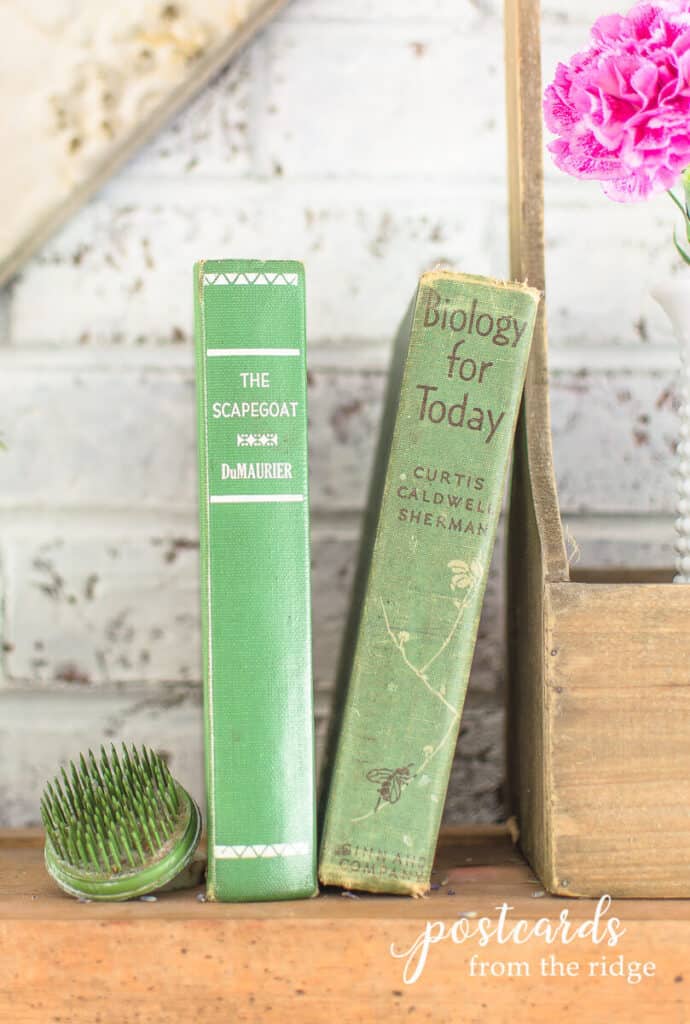 vintage green books on spring mantel with vintage green metal spike flower frog