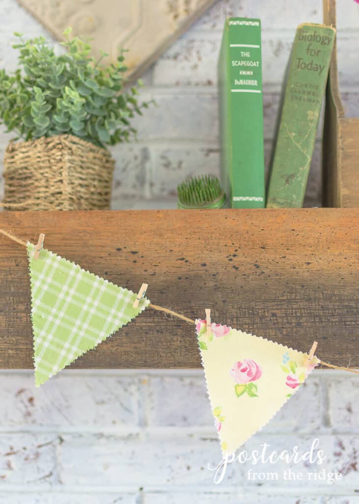 spring mantel with pastel fabric banner and vintage green books