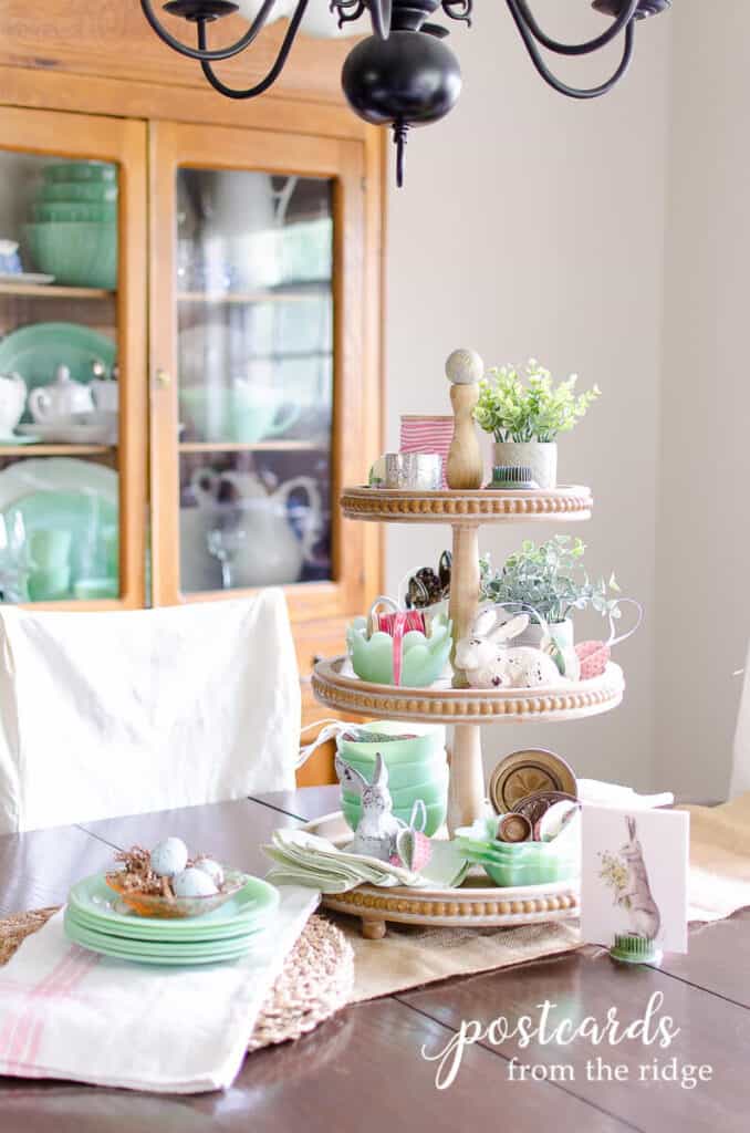 spring centerpiece with wooden tiered tray filled with vintage jadeite dishes and little cast iron bunnies