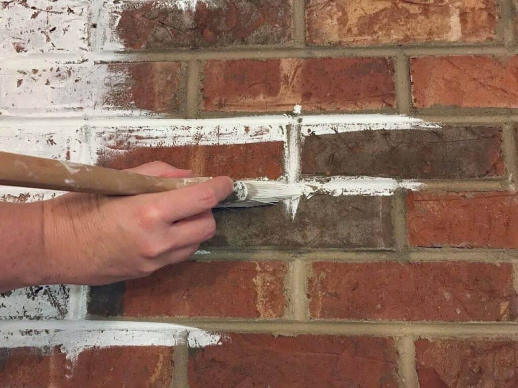 applying paint to red brick fireplace