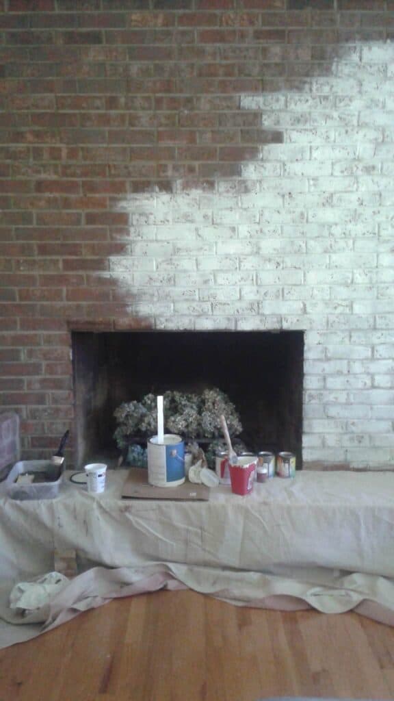 red brick fireplace with white paint being applied