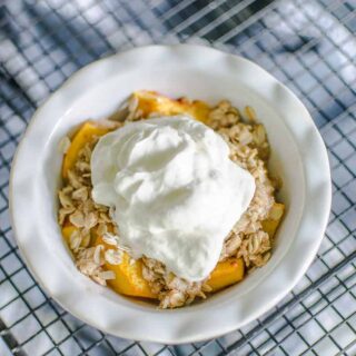 peach crisp in small dish with whipped cream