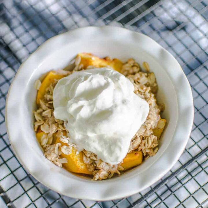 peach crisp in small dish with whipped cream