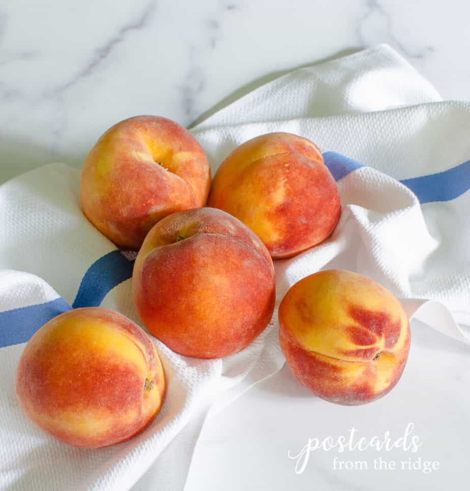 fresh peaches on a blue and white striped kitchen towel