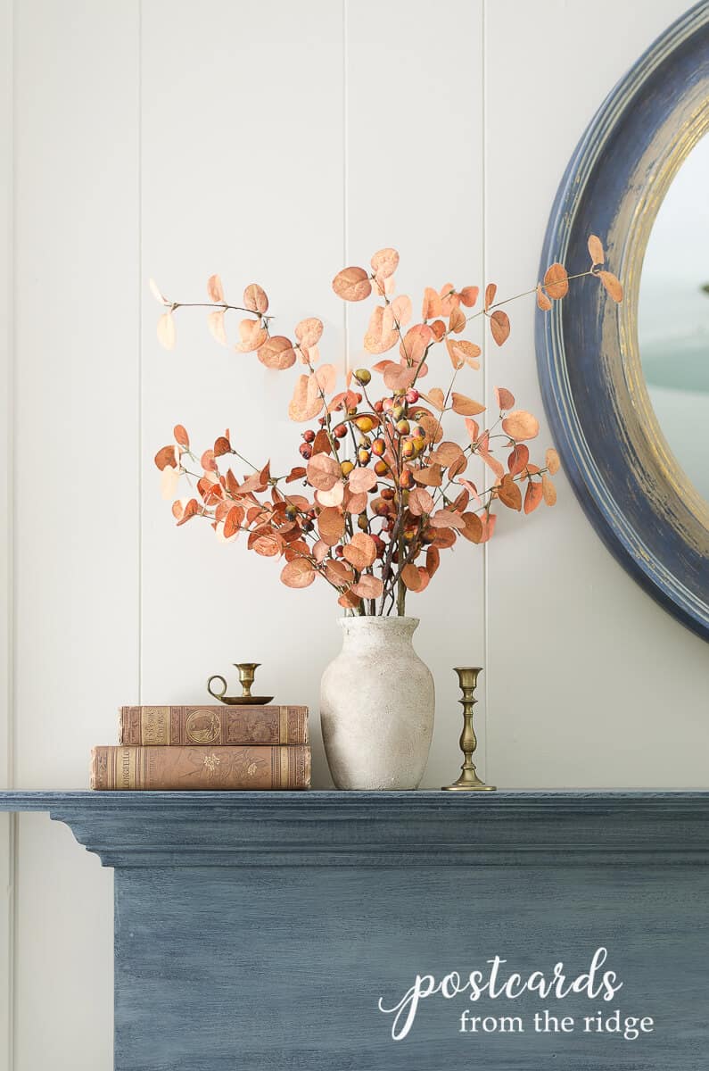 glass vase painted to look like stoneware with faux fall branches on blue mantel