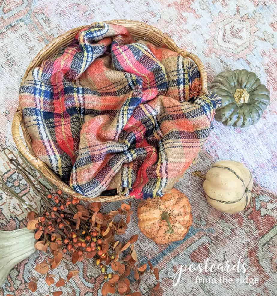 large basket with plaid blanket scarf and faux pumpkins
