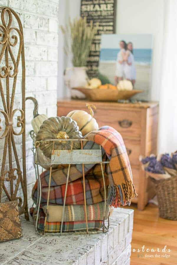 realistic faux pumpkins and plaid blankets in wire egg crate